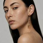 Close-up of a woman wearing gold earrings with a neutral background