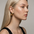 Woman wearing gold earrings with a neutral background