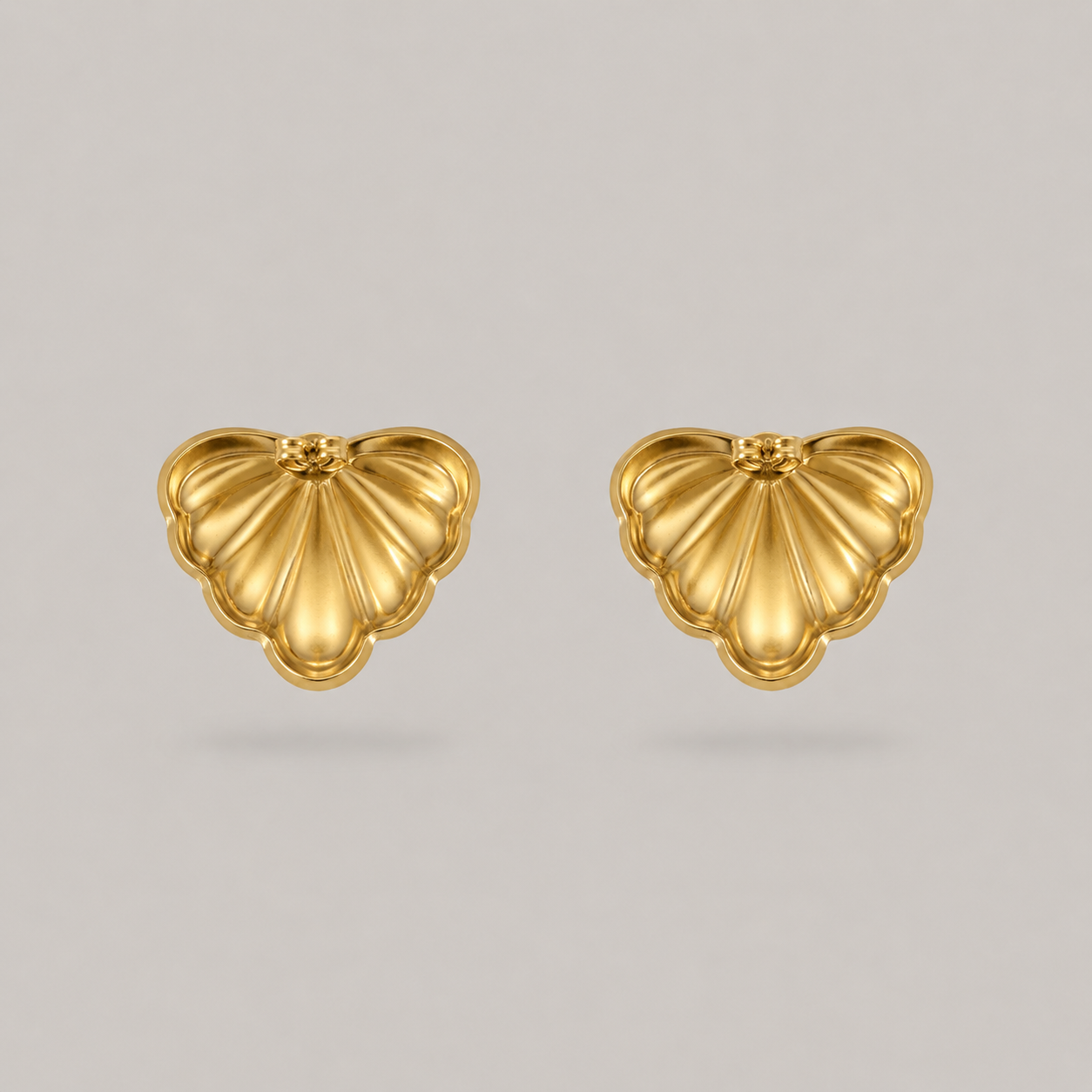 Pair of gold heart-shaped earrings on a light gray background