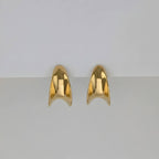Gold earrings on a light gray background