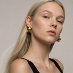 Woman wearing gold hoop earrings against a neutral background