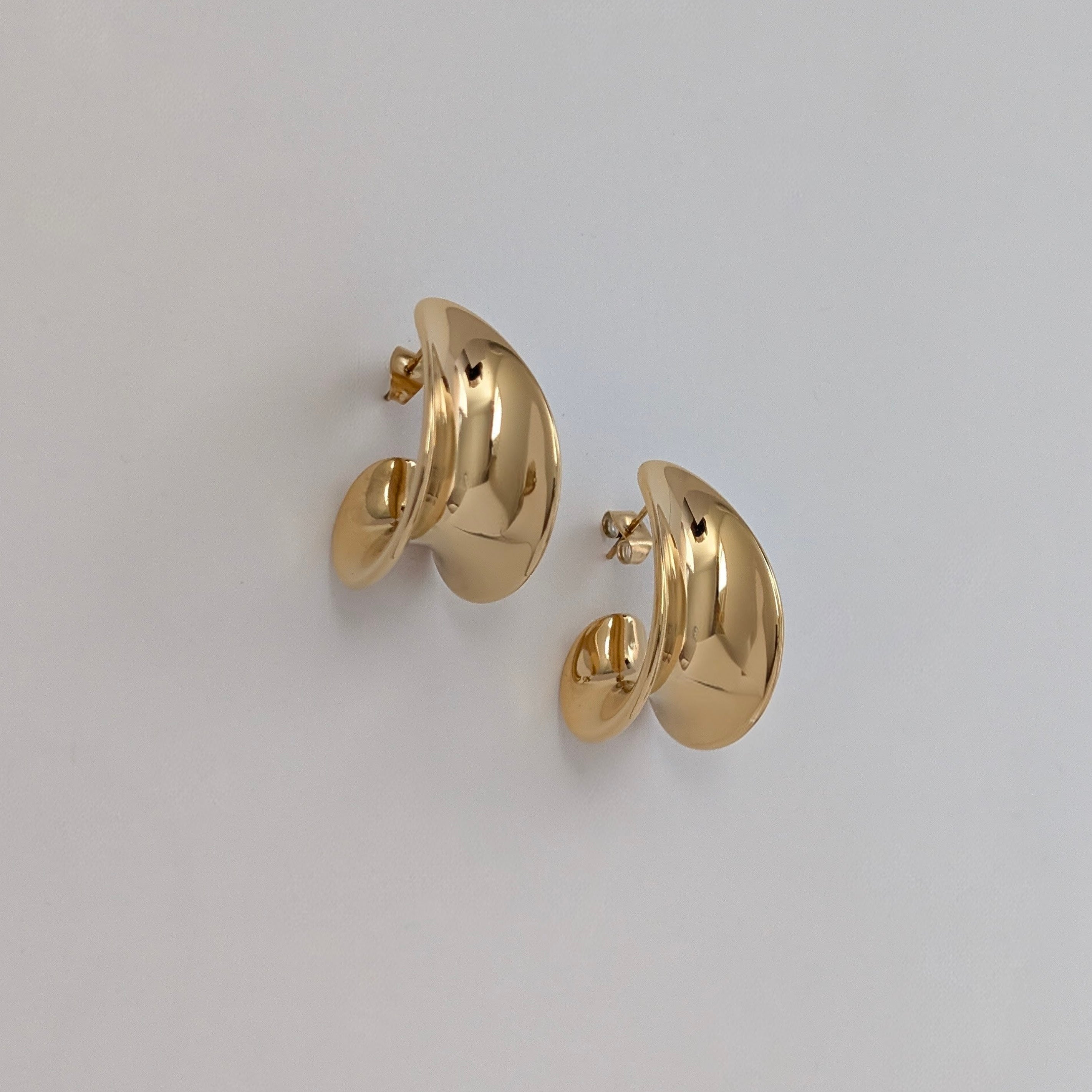 Gold hoop earrings on a light gray background