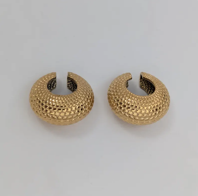 Pair of gold ear cuff on a light gray background