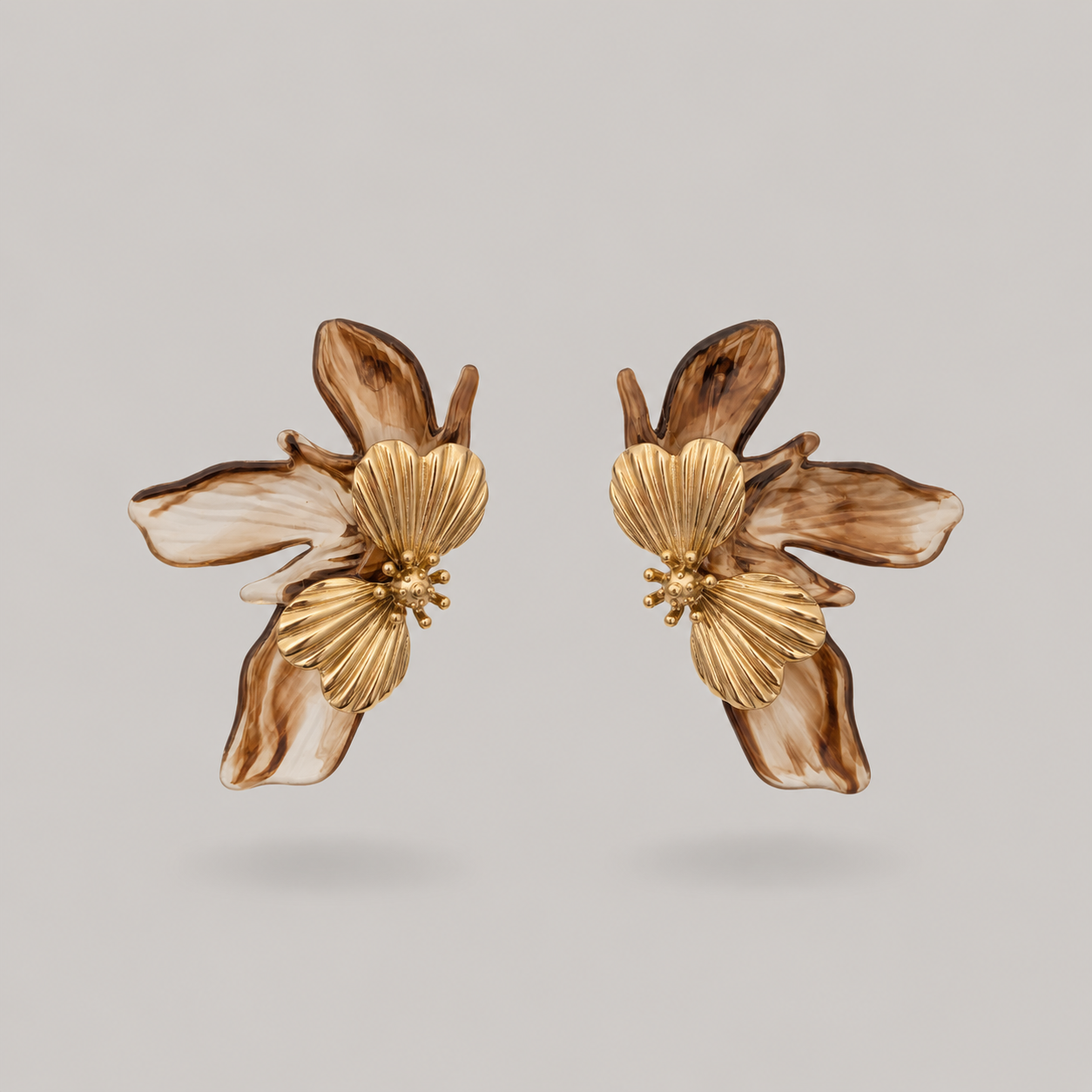 Pair of gold floral earrings on a light gray background