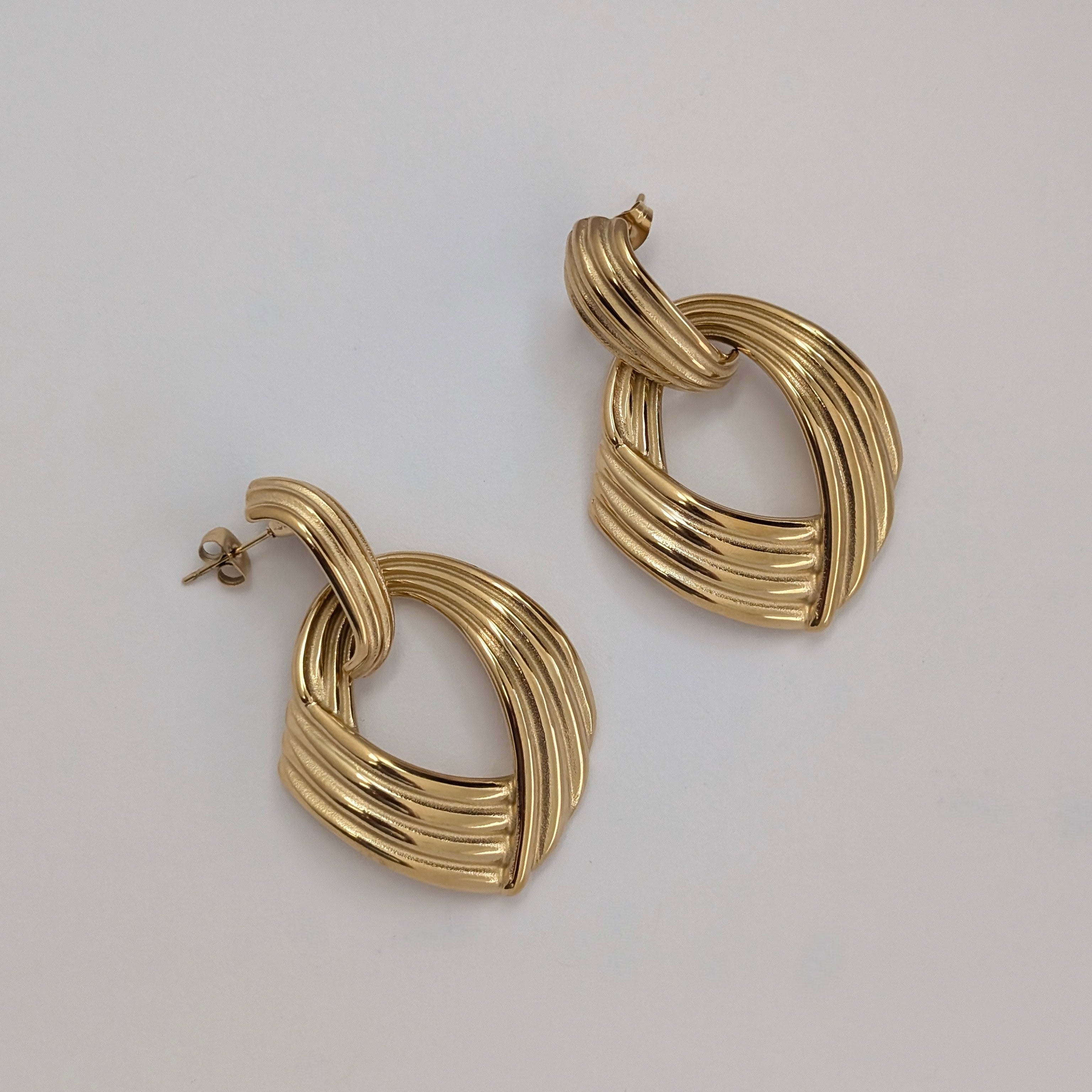 Pair of gold earrings on a light gray background