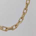 Gold chain bracelet on a light gray background