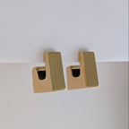 Gold rectangular earrings on a light gray background