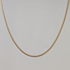 Gold chain necklace on a light gray background