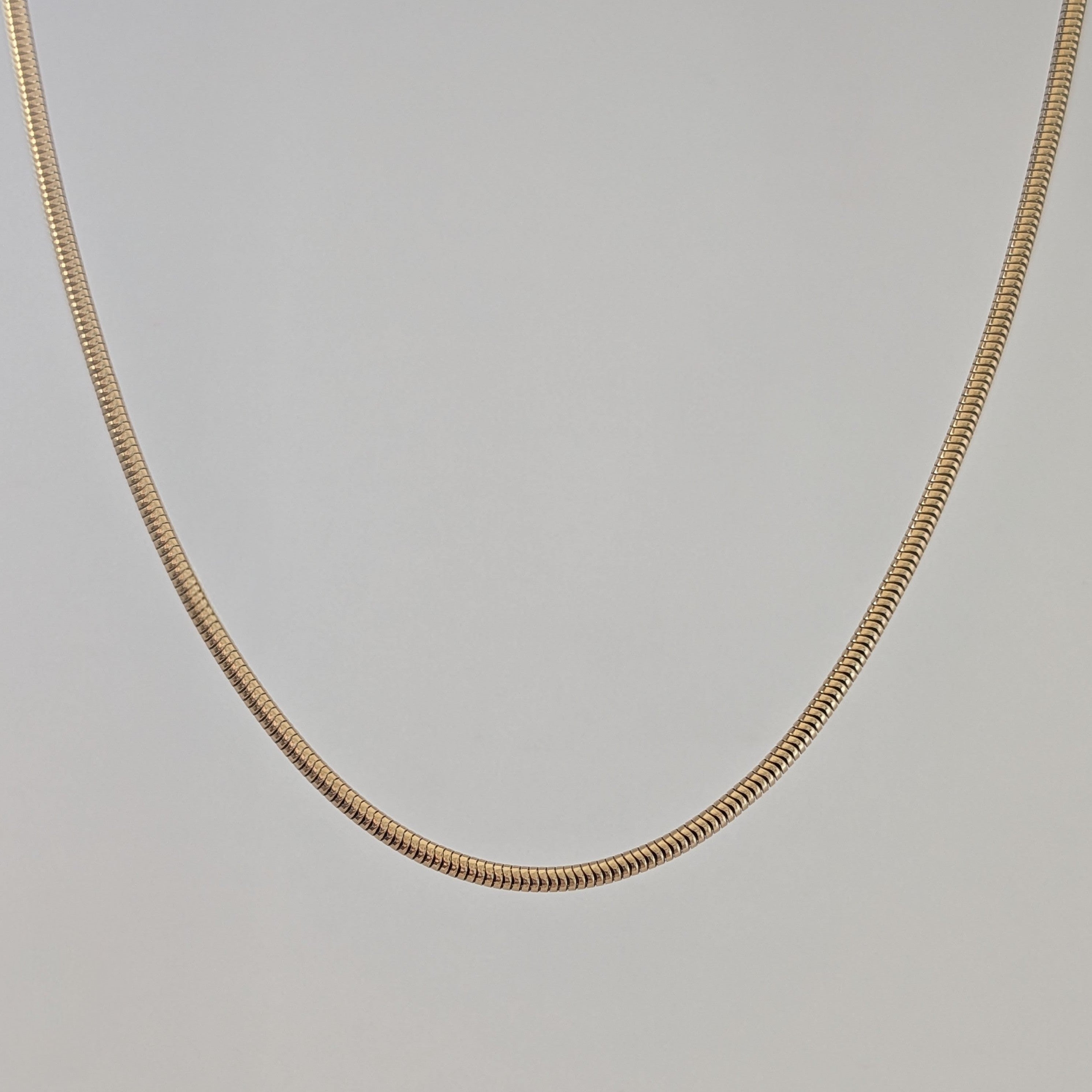Gold chain necklace on a light gray background