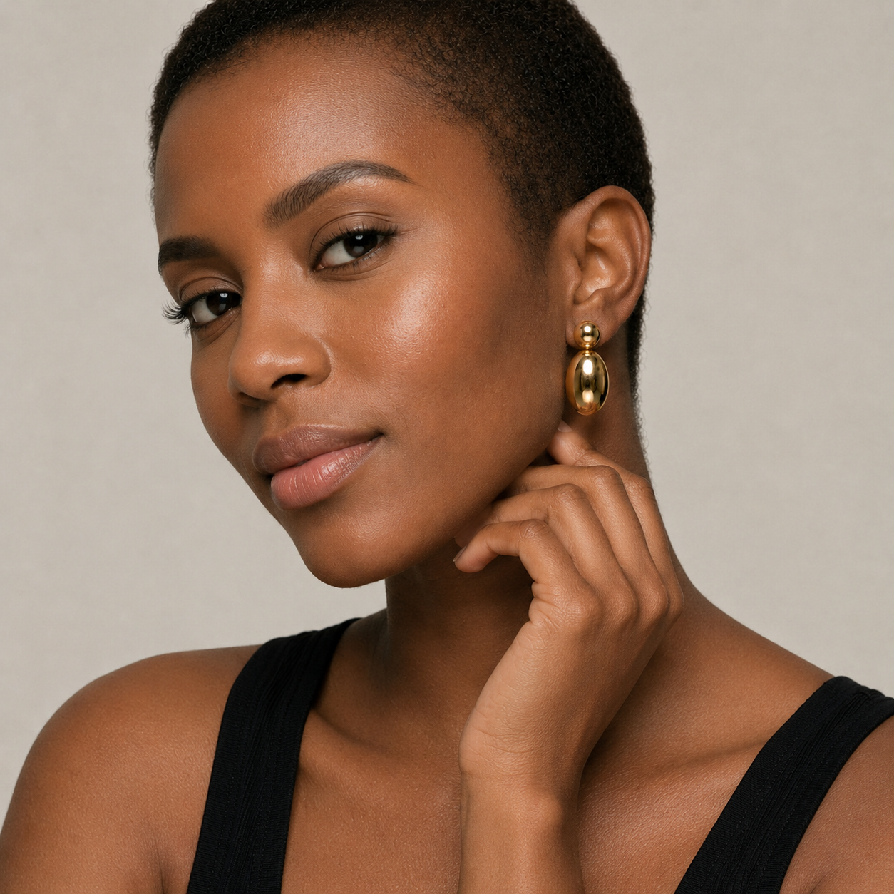 Woman wearing gold earrings with a neutral background
