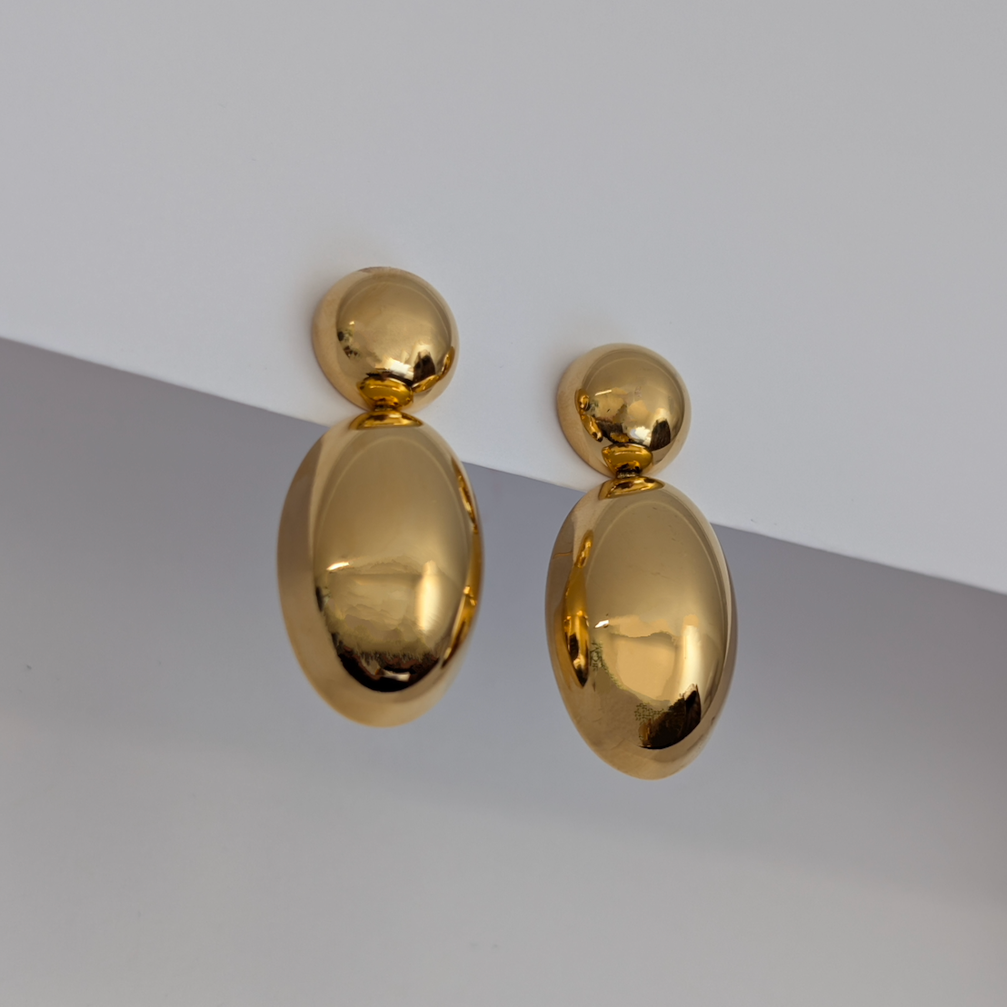 Pair of gold earrings on a gray and white background