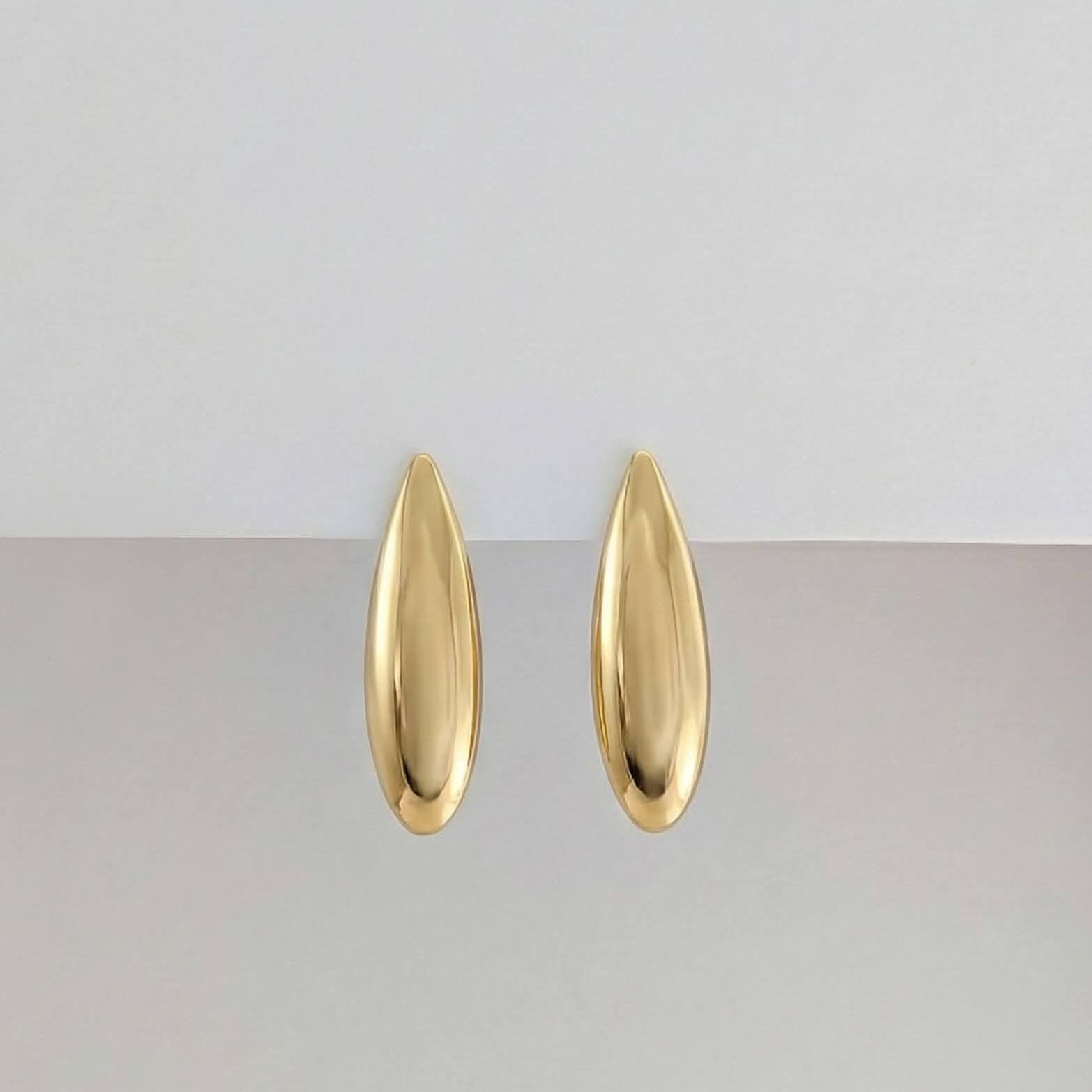 Gold earrings on a light gray background