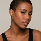 Woman wearing gold earrings with a neutral background