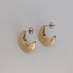 Gold hoop earrings on a light gray background
