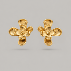 A pair of gold flower-shaped stud earrings with textured petals and a polished center, displayed on a neutral gray background.