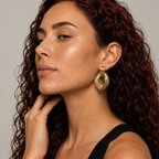 Woman wearing gold door knocker earrings with a neutral background