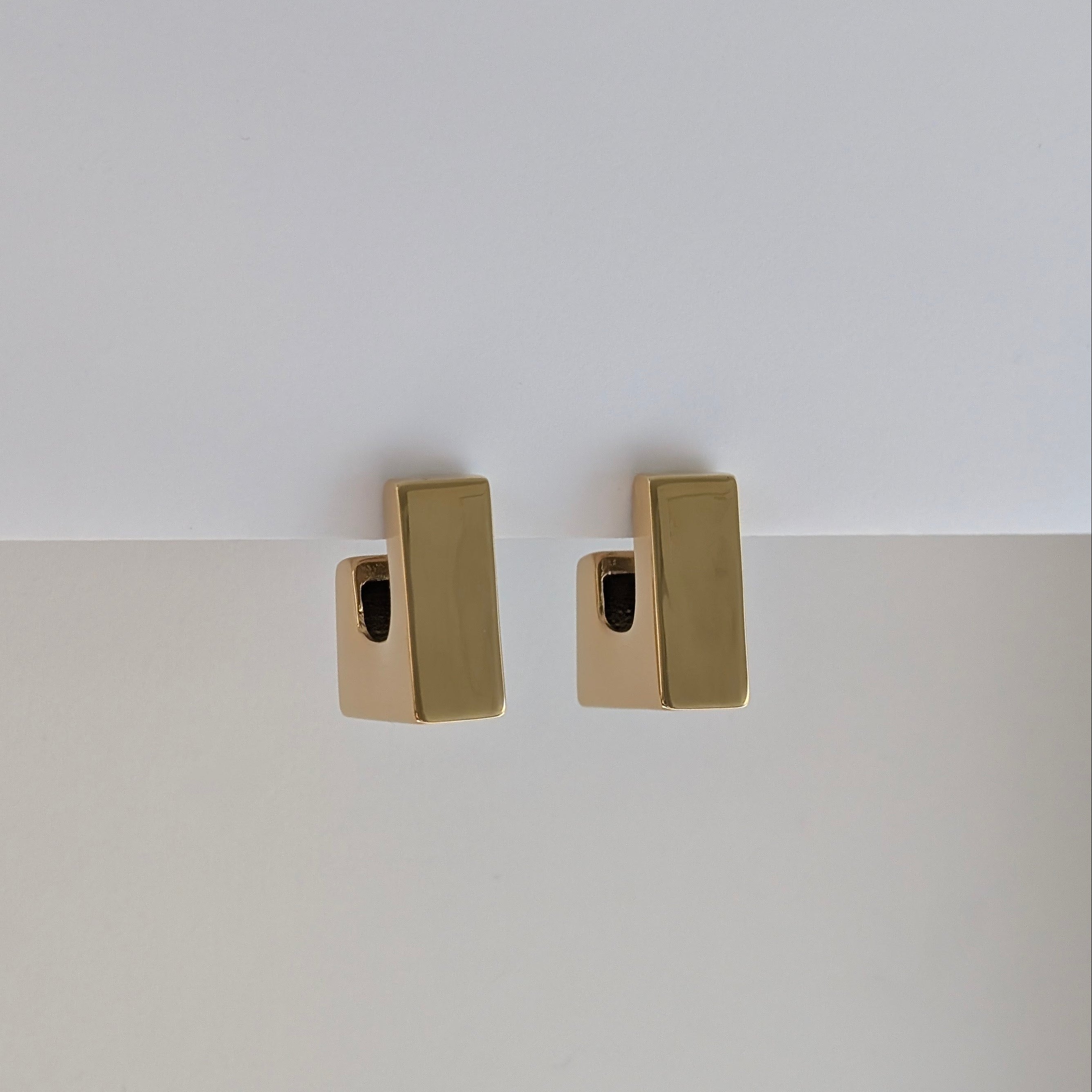 Gold rectangular earrings on a white background