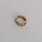 Gold ear cuff with blue stones on a light gray background