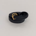 Side profile of gold twisted ear cuff on black silicone ear.