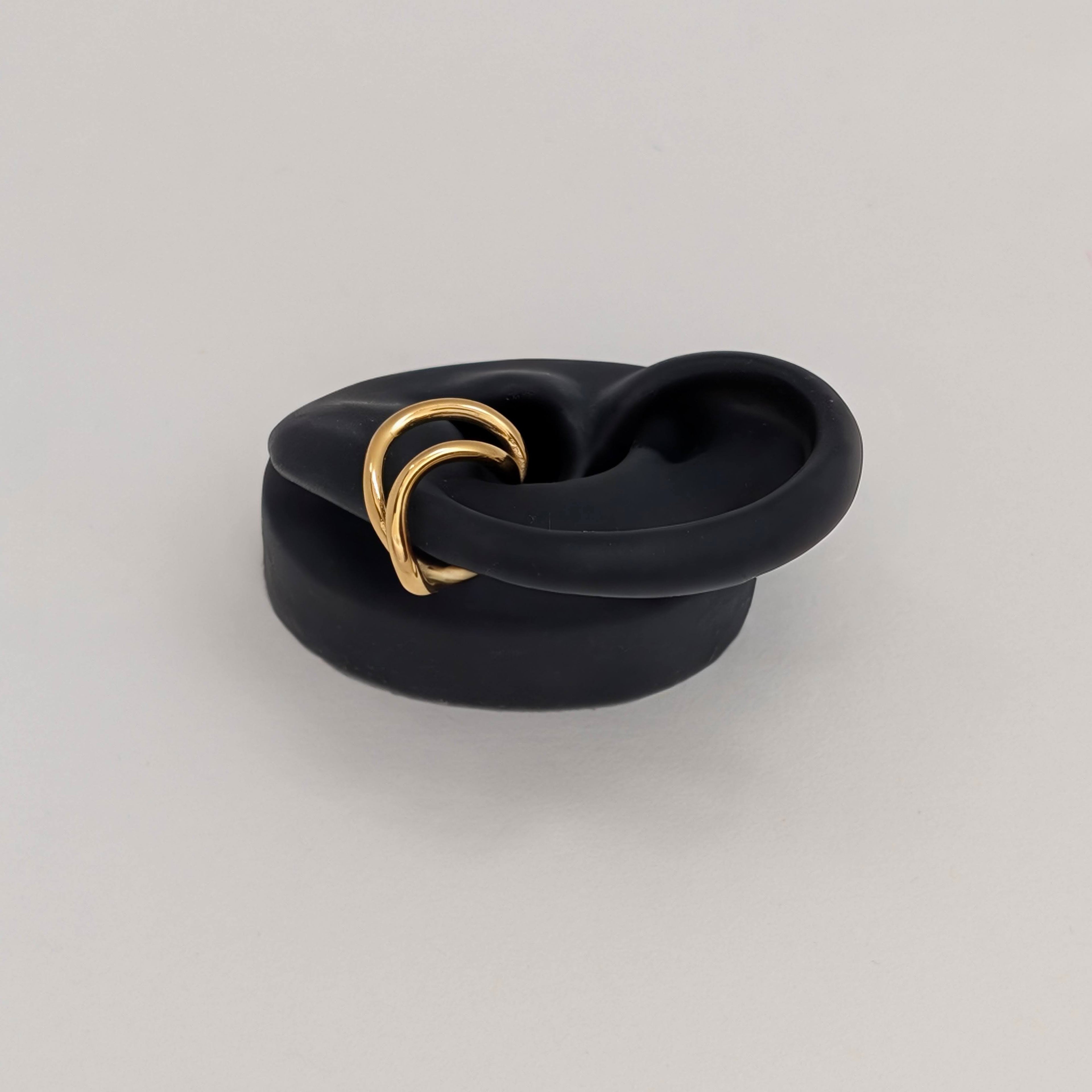 Side profile of gold twisted ear cuff on black silicone ear.