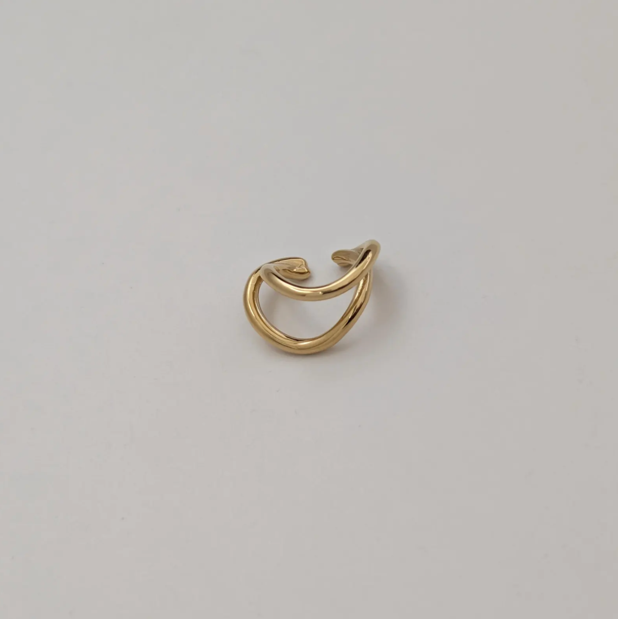 Gold ear cuff on a light gray background