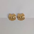 A pair of large gold vintage stud earrings with a rippled texture, displayed against a white background.