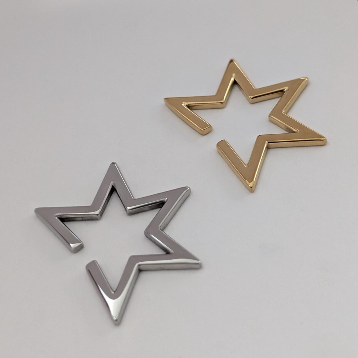 Two star-shaped Ear Cuffs, one gold and one silver, on a white background.