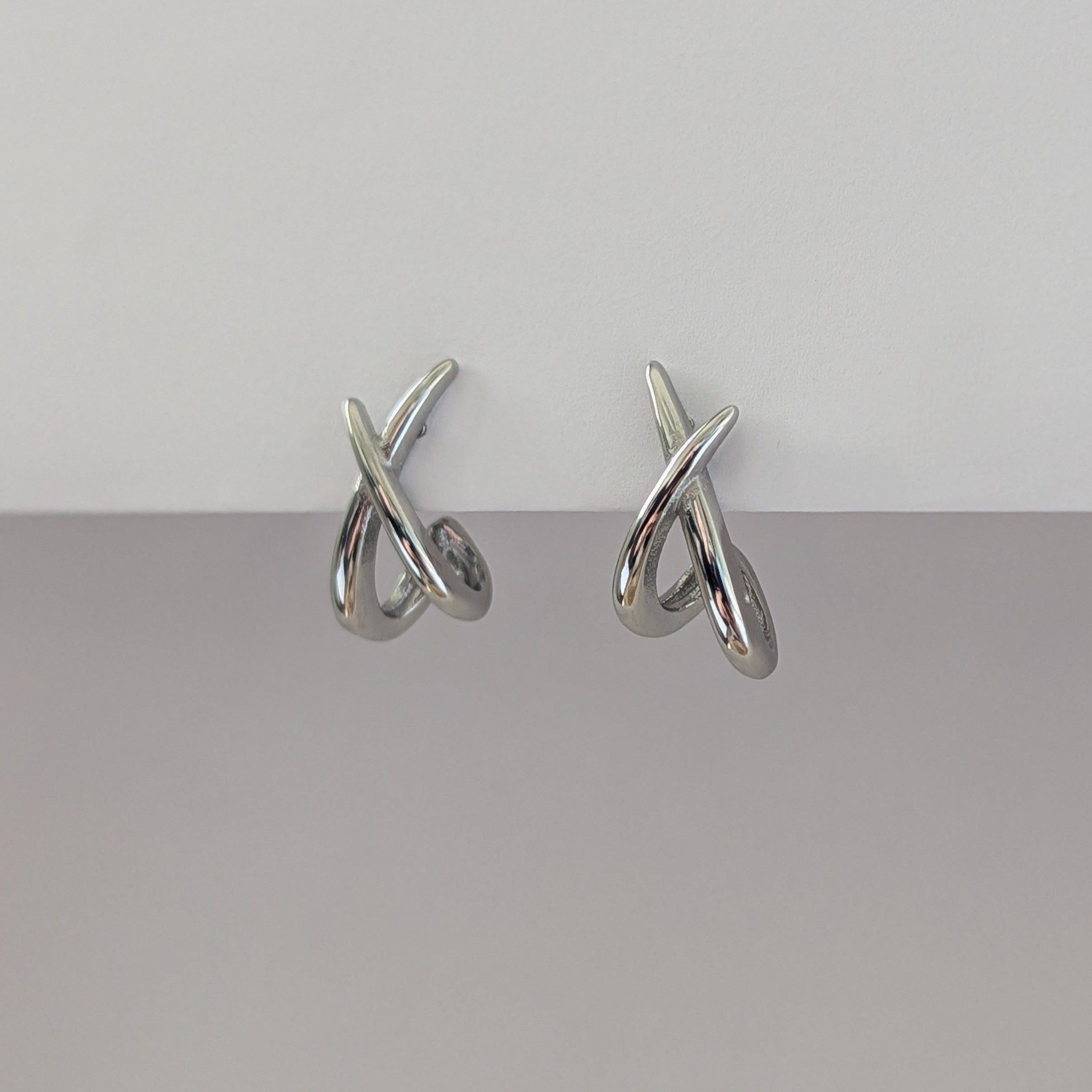 Pair of silver earrings on a gray background