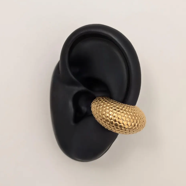Gold textured earring on a black ear model against a light gray background