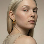 Woman wearing gold hoop earrings against a neutral background
