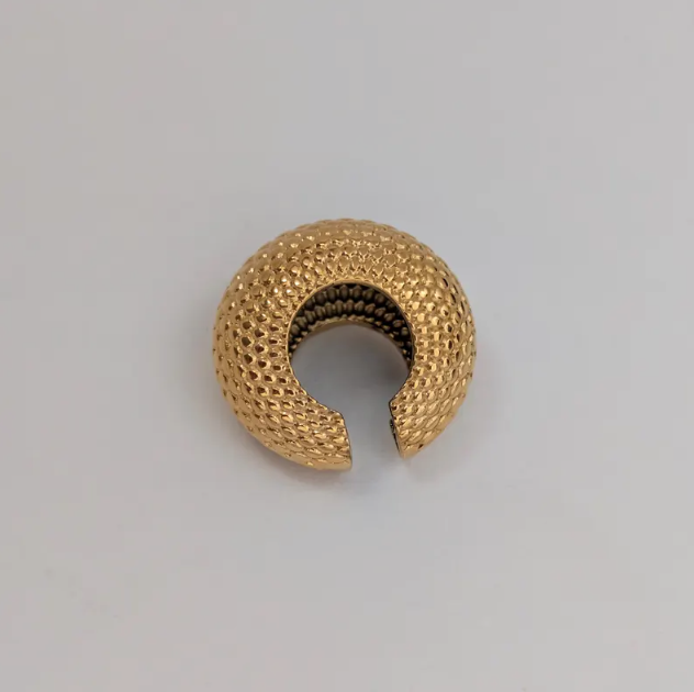 Gold ear cuff on a gray background