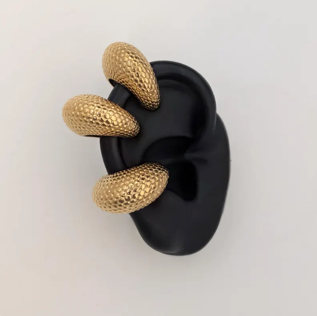 Gold cuff on a black ear model against a white background