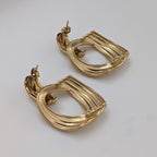 Back of gold earrings on a light gray background