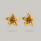 A pair of gold flower-shaped stud earrings with five petals and a textured center, displayed on a neutral gray background.
