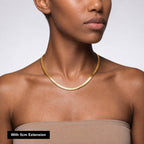 Woman wearing a gold necklace with a 5cm extension on a plain background