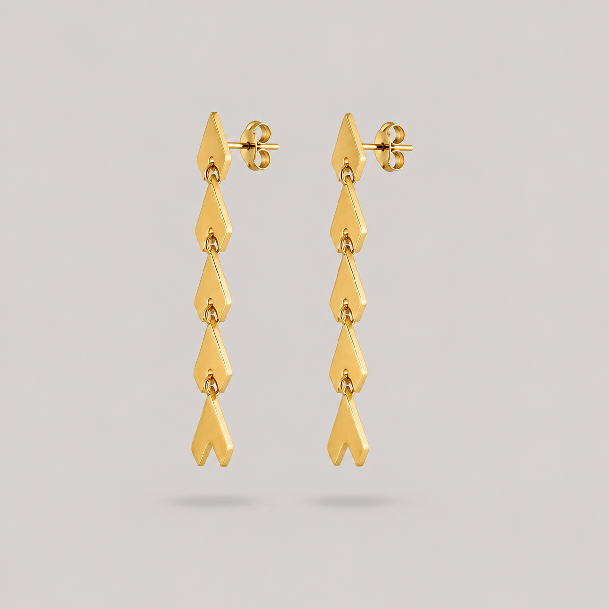 Gold earrings on a light gray background