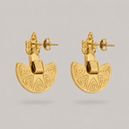Pair of gold earrings with geometric design on a gray background