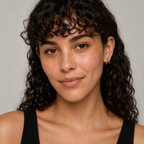 Woman with curly hair wearing a black top against a neutral background