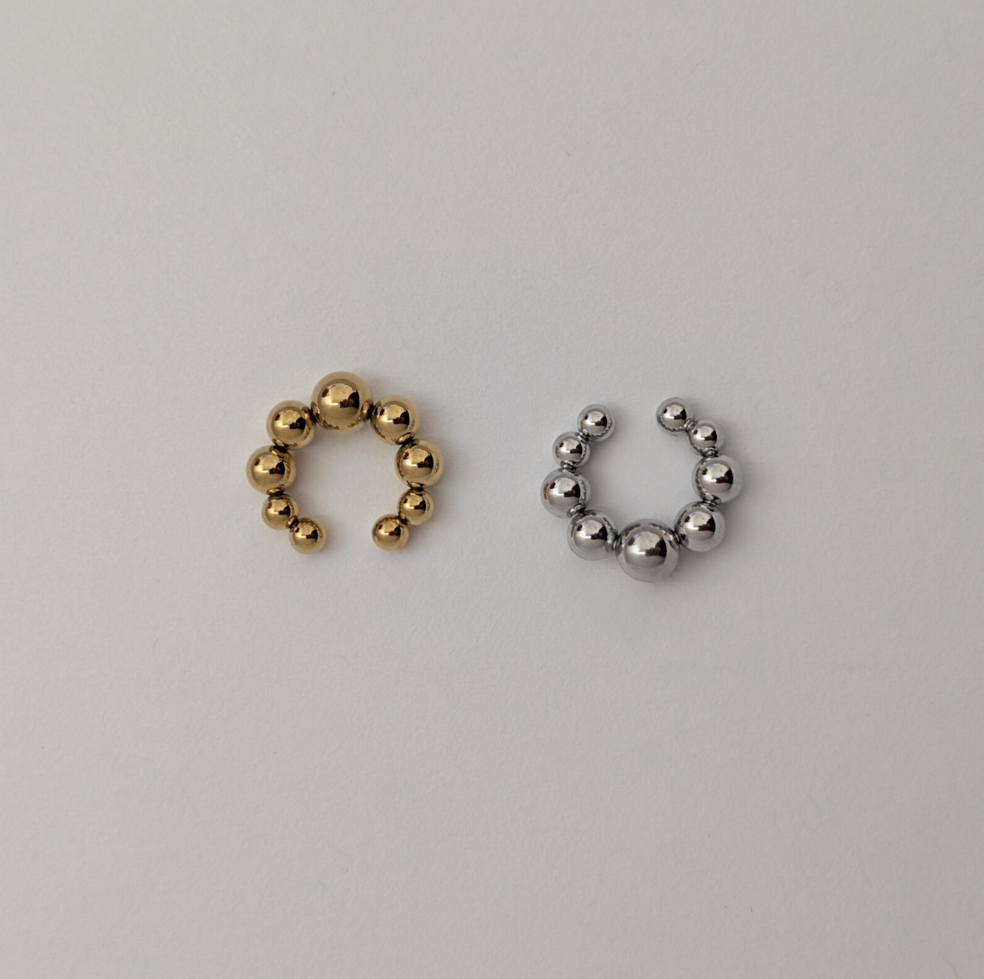 Gold and silver beaded hoop ear cuffs on a light gray background