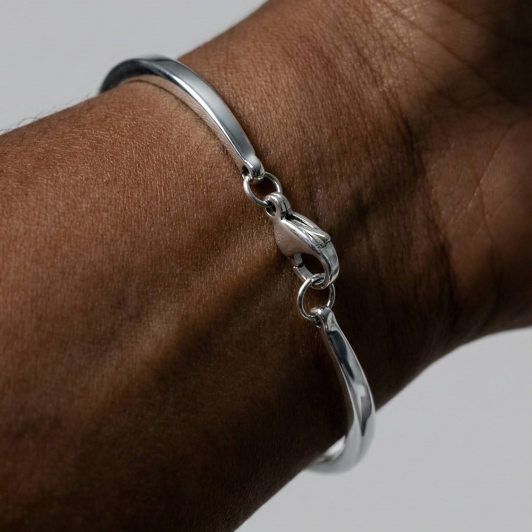 Gold and Silver eye bracelet on a wrist against a neutral background