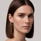 Close-up of a woman wearing gold earrings with a neutral background