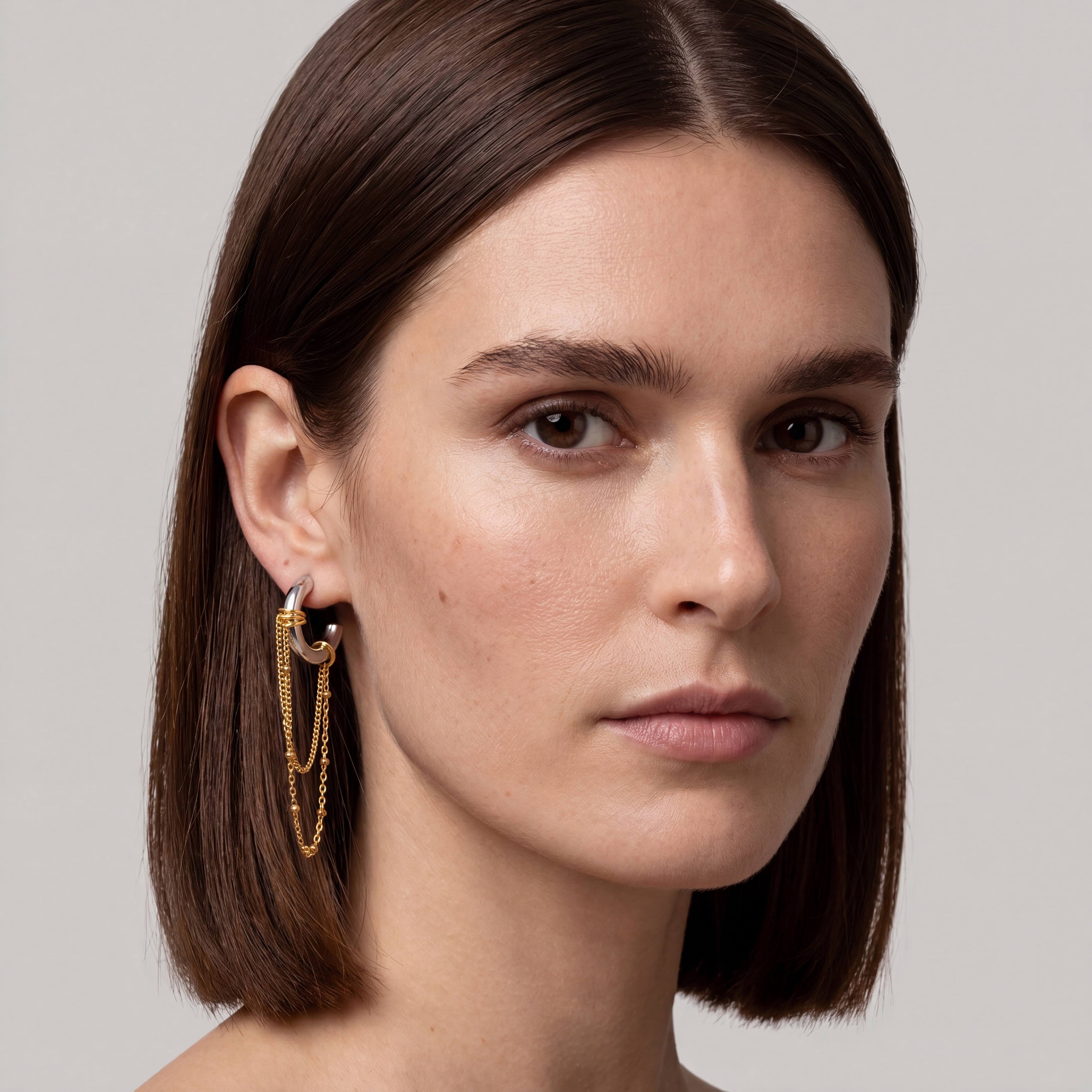 Close-up of a woman wearing gold earrings with a neutral background