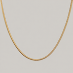 Gold chain necklace on a light gray background