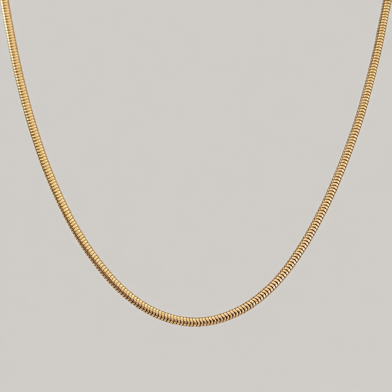 Gold chain necklace on a light gray background