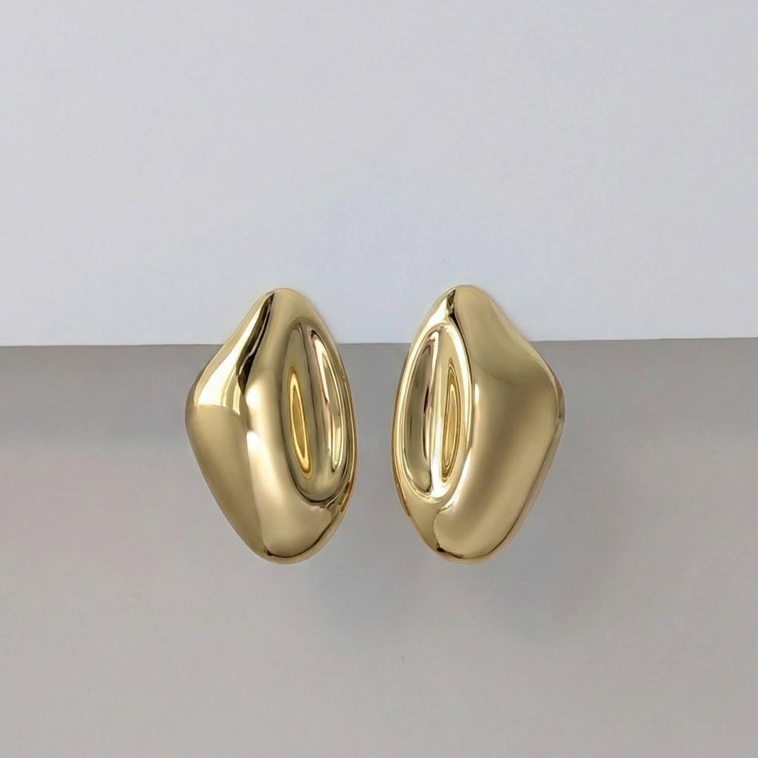 Gold earrings on a light gray background