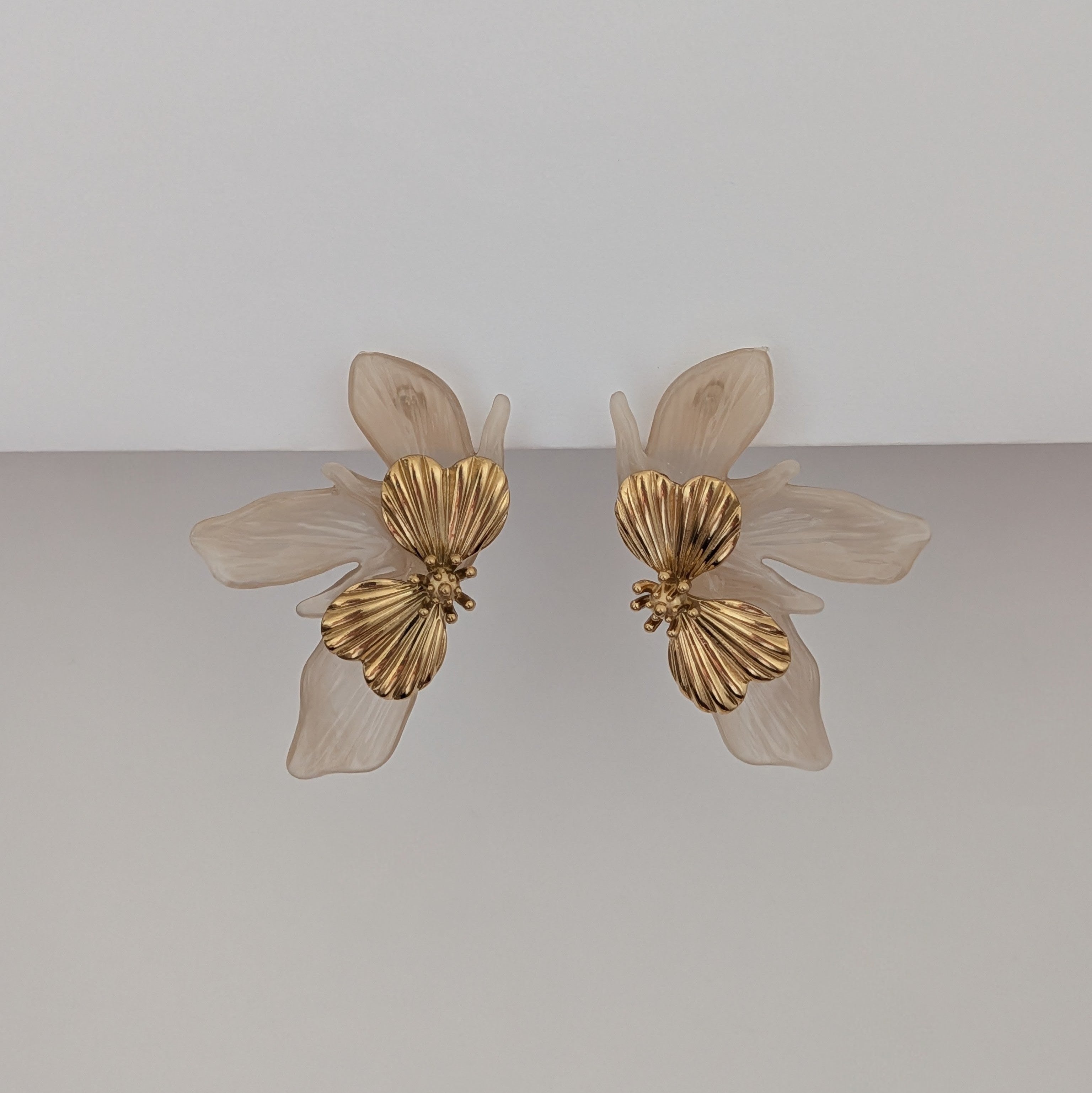Pair of gold butterfly earrings on a light gray background