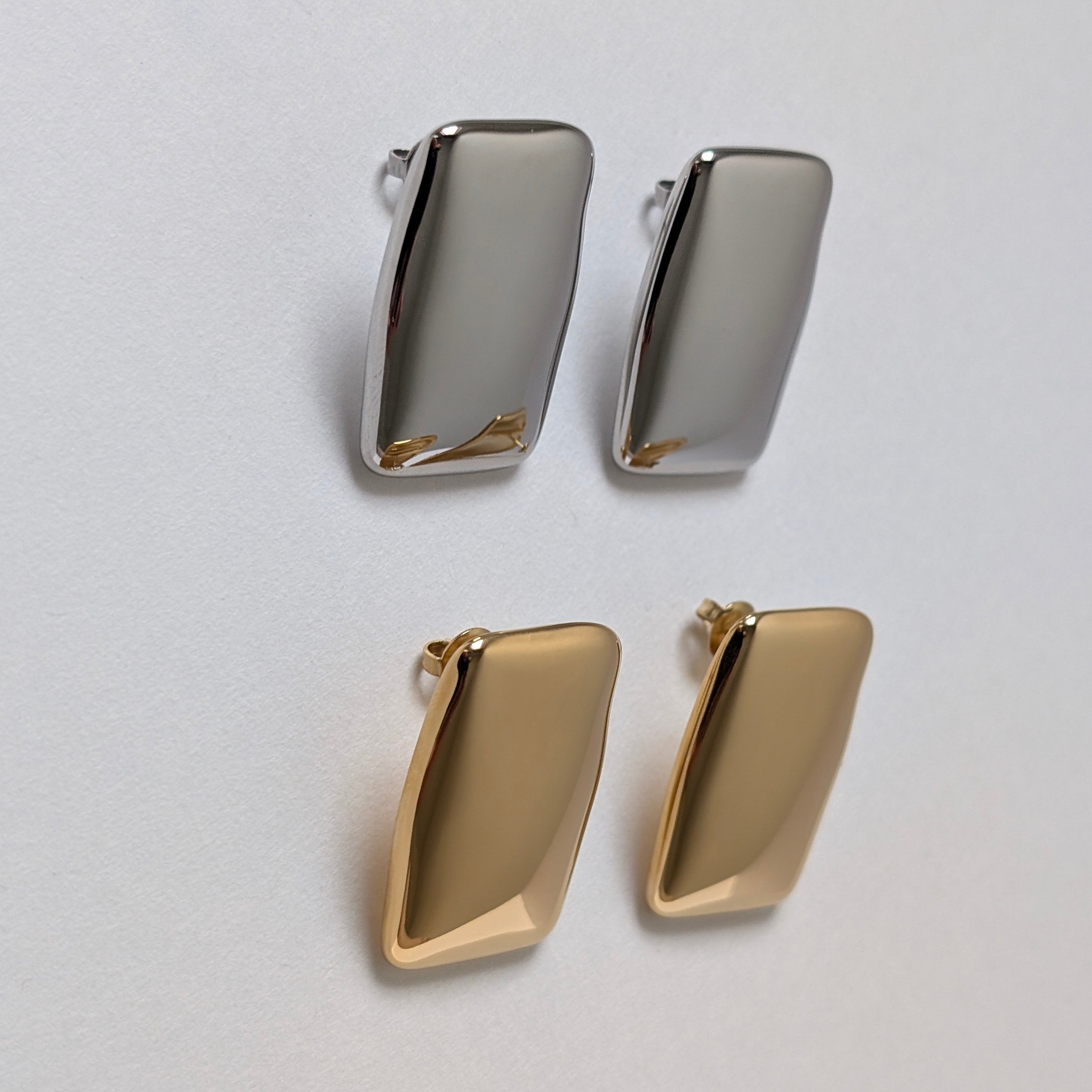 Pair of gold and silver earrings on a light gray background