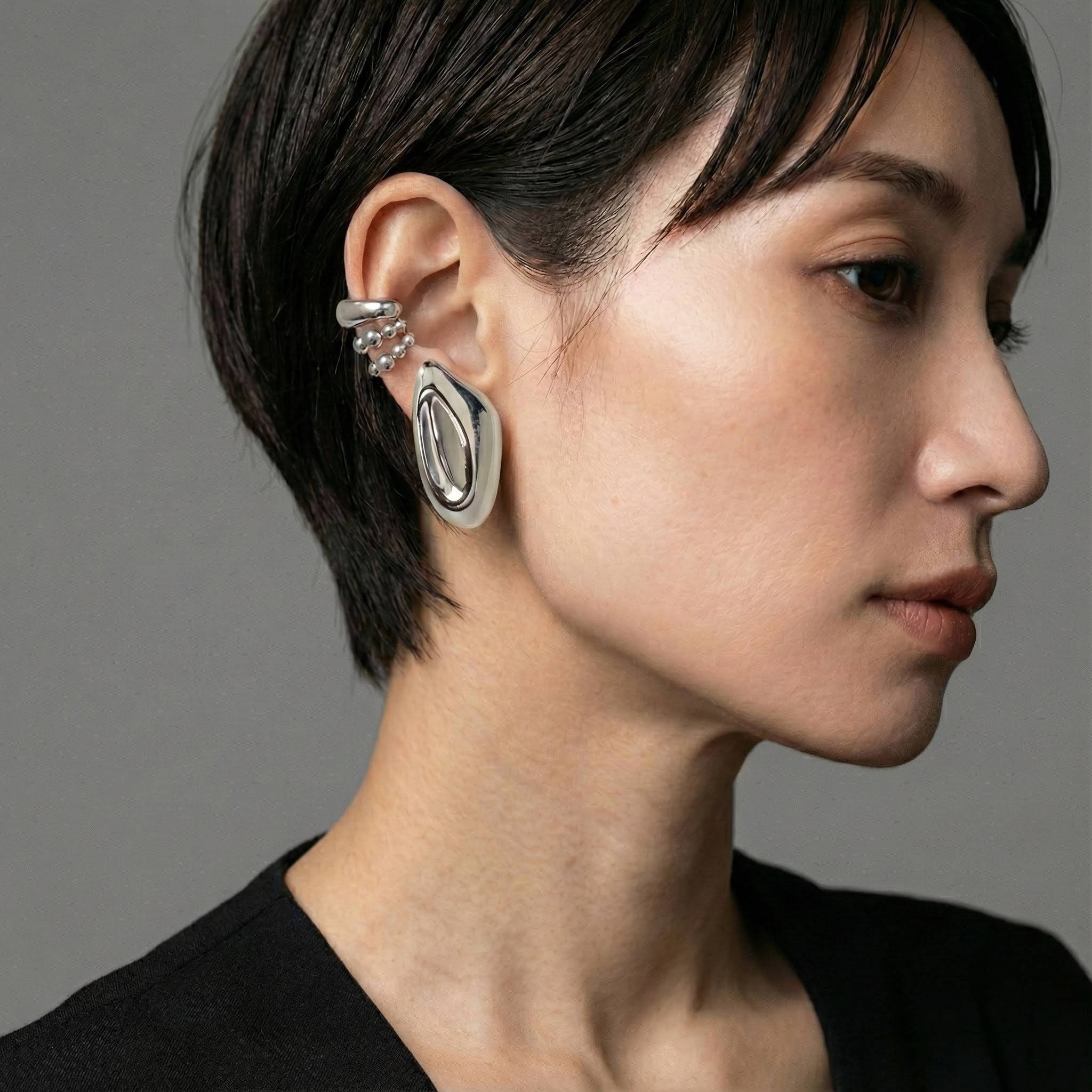 Close-up of a person wearing a silver earring on a gray background