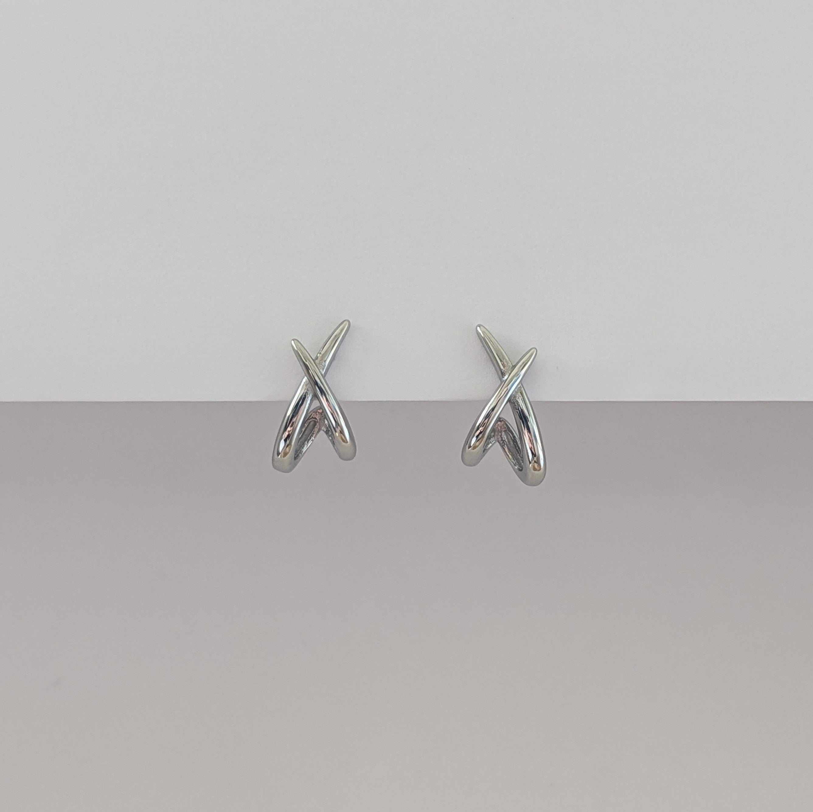 Pair of silver earrings on a gray background