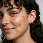 Close-up of a woman wearing a silver earring with a neutral background